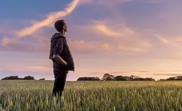 man in field looking at sky